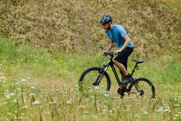 Mountain Biker montando sua bicicleta através do prado — Fotografia de Stock