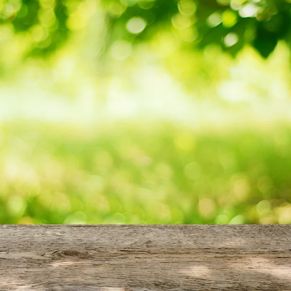 Lege houten tafel in de tuin met heldere groene achtergrond — Stockfoto