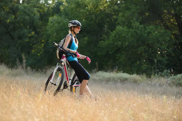 Joven atractiva mujer descansando con bicicleta en el hermoso bosque —  Fotos de Stock