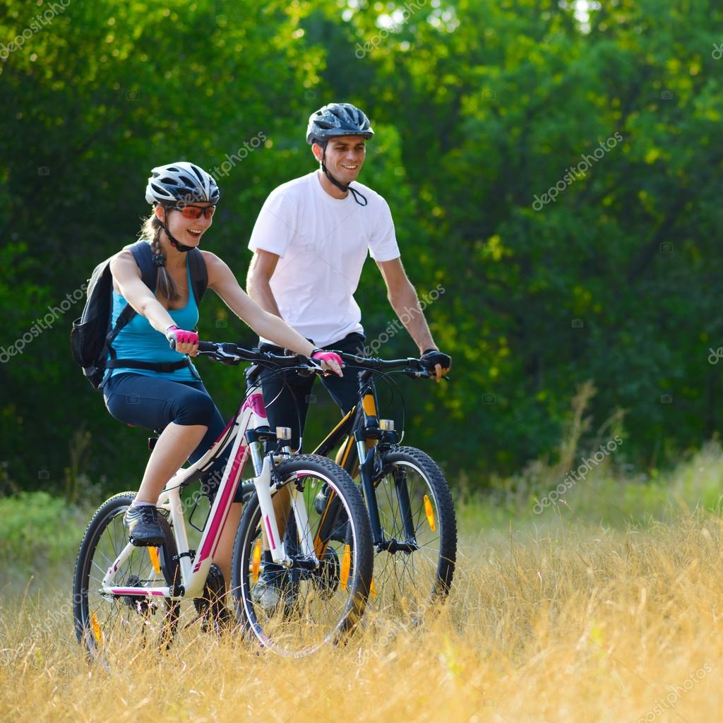 Young Happy Couple Riding Mountain Bikes Outdoor Stock Photo by