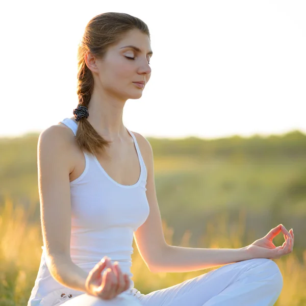 Jovem bela mulher pratica Yoga no prado ensolarado — Fotografia de Stock