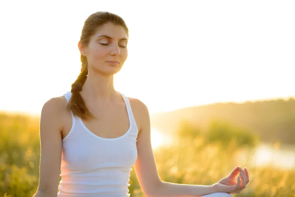 Jovem bela mulher pratica Yoga no prado ensolarado — Fotografia de Stock