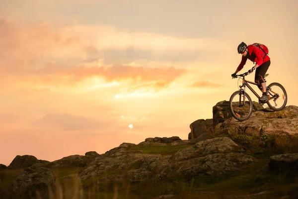 Radfahrer im Rotkäppchen auf dem Sommer-Rocky-Trail bei Sonnenuntergang. Extremsport und Enduro-Konzept. — Stockfoto