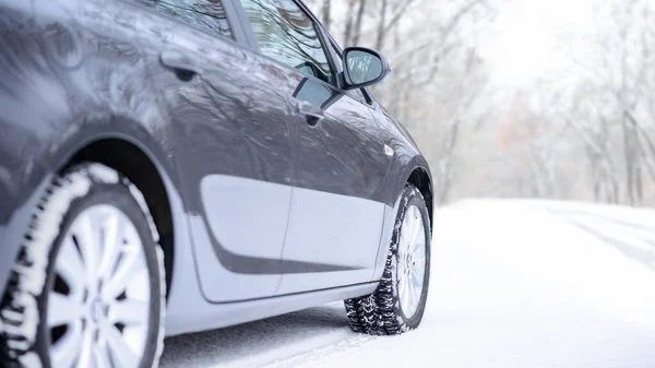Auto na Zimní cestě. Detailní záběr na zimní auto pneumatiky na zasněžené silnici. Koncepce bezpečné jízdy. — Stock fotografie