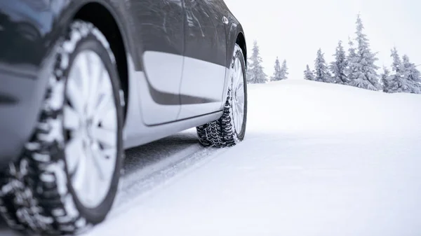 Coche en la carretera de invierno. Imagen de cerca del neumático de invierno en la carretera nevada. Concepto de conducción segura. — Foto de Stock