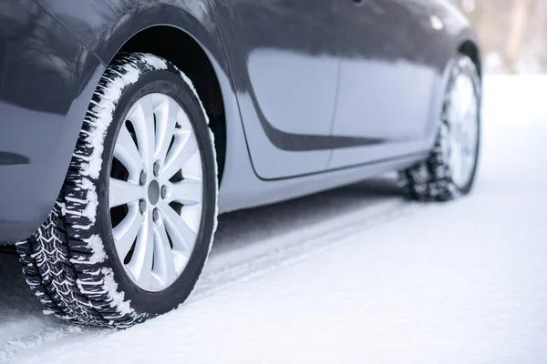 Auto na Zimní cestě. Detailní záběr na zimní auto pneumatiky na zasněžené silnici. Koncepce bezpečné jízdy. — Stock fotografie