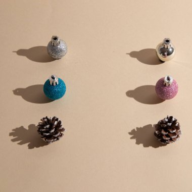 Farklı renklerde yeni yıl süslemeleri ve bej arka planda fotokopi alanı olan iki koni. Minimalist sahne.