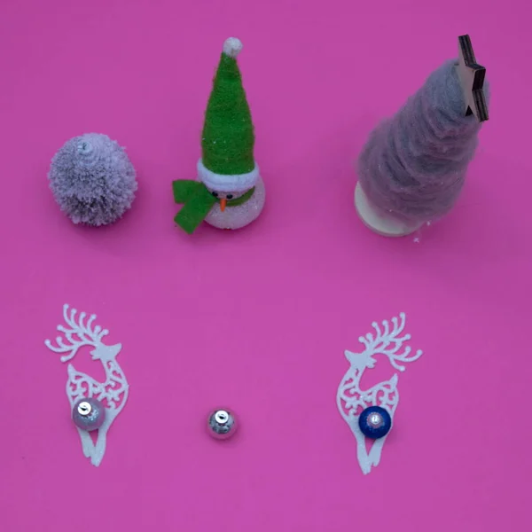 Pembe arka planda yeni yıl ve Noel süslemeleri. Noel ağacının hakimiyeti ve geyikli kardan adam. Asgari konsept.