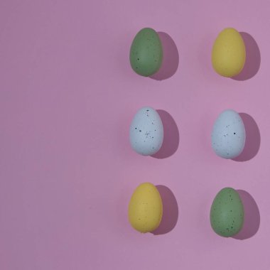 Farklı renklerde Paskalya yumurtaları. Pembe arka planda hafif gölgeler ve sağ tarafta kopyalama alanı var. Minimalist Paskalya sahnesi.