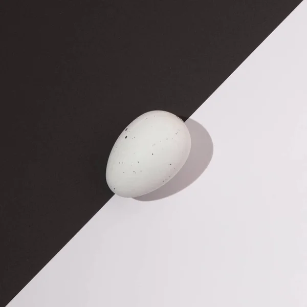 Beyaz Paskalya yumurtası siyah beyaz arka planda yumurtayı ikiye böler. Minimalist Paskalya sahnesi.