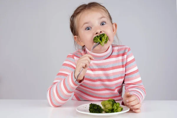 Ребенок ест брокколи с аппетитом. Органическая капуста и еда на тарелке. Зеленые здоровые овощи, богатые витаминами. — стоковое фото