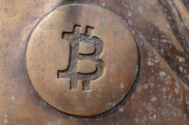 a bitcoin icon on a bronze statue
