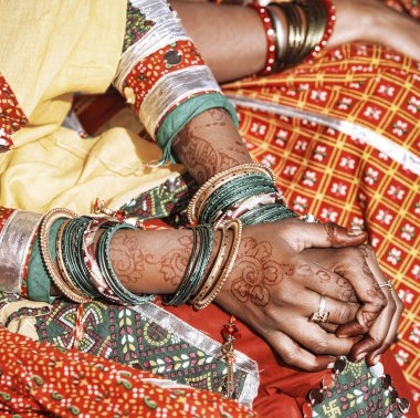Hands of a young Indian woman adorned with traditional bangles and mehndi. 