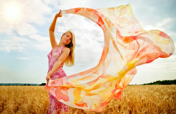 Молодая женщина в поле держит шарф, чтобы ветер . — стоковое фото