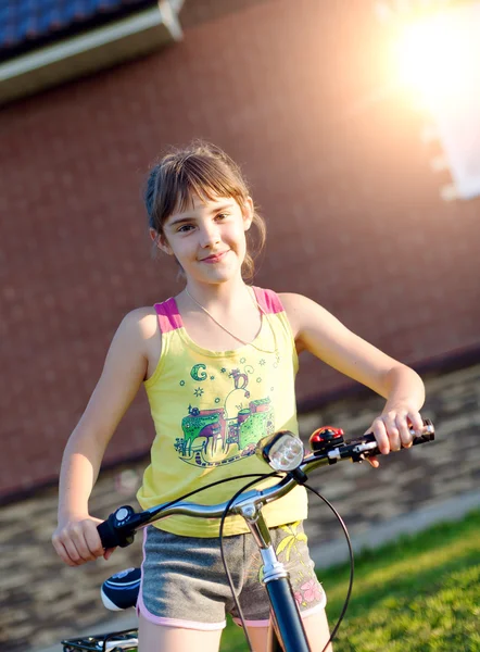 Girl on a bicycle against the brick wall at house — Stock Photo, Image