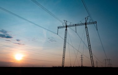 Akşam gökyüzü arkaplanındaki elektrik hatları