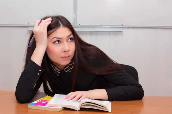 Student sitting in a classroom with books — Stock Photo, Image