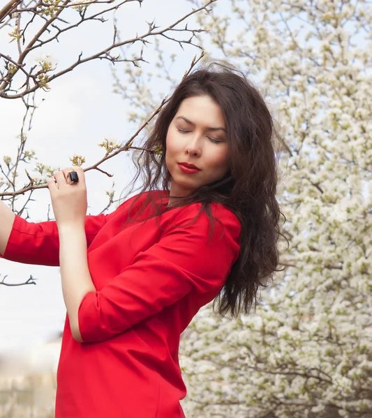 Krásná dívka v červených šatech. kvetoucí jablko — Stock fotografie