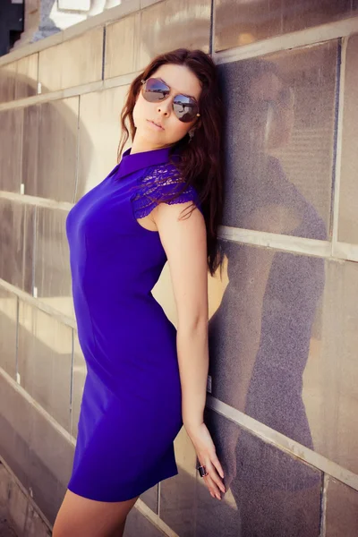 Schöne sexy Frau in einem blauen Kleid und Sonnenbrille auf der Straße an einem Sommertag — Stockfoto
