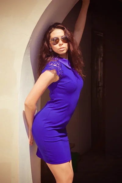 Belle femme sexy dans une robe bleue et des lunettes de soleil dans la rue un jour d'été — Photo