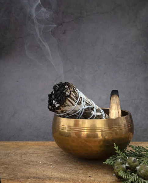 white sage incense and singing bowl in front of white background