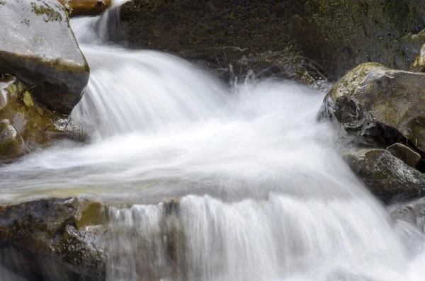 Cascade putoaa yli sammaltava kiviä — kuvapankkivalokuva