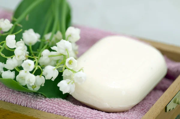 Spa setting of towels, soap and lilies of the valley — Stock Photo, Image