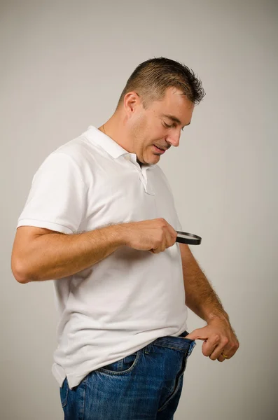 Kerl mit Größensorgen und Auschecken mit der Lupe — Stockbild Größensorgen — Stockfoto