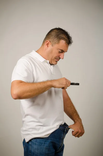 Kerl mit Größensorgen und Auschecken mit der Lupe — Stockbild Größensorgen — Stockfoto