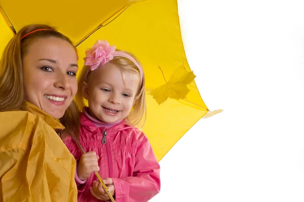 Mutter und kleine Tochter unter gelbem Regenschirm — Stockfoto