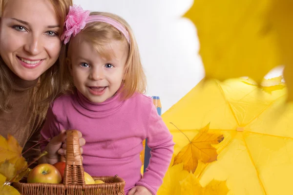 Madre e hija pequeña con cesta y hojas — Foto de Stock