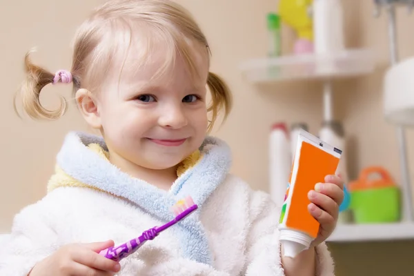 Chica sonriente con cepillo de dientes y tubo Imagen De Stock