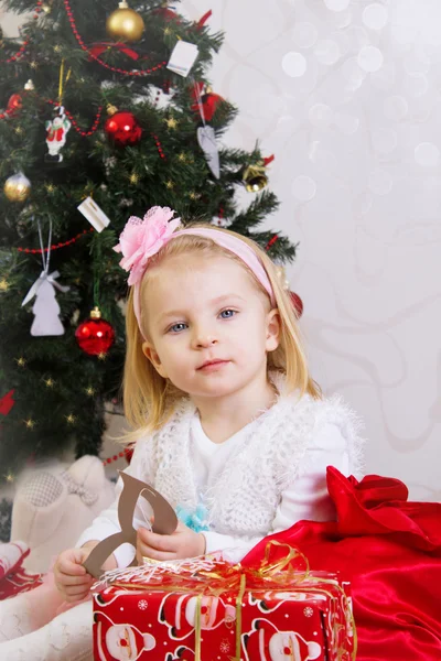 Κορίτσι στο ροζ κάτω από το χριστουγεννιάτικο δέντρο — Φωτογραφία Αρχείου