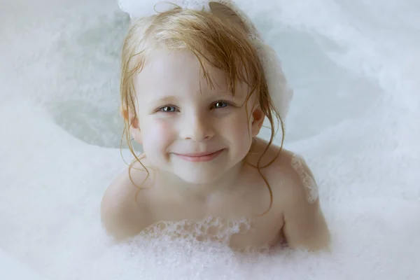 Fille avec un bouchon de mousse sur la tête dans le bain — Photo