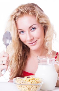 Smiling woman with spoon, milk and corn-falkes clipart