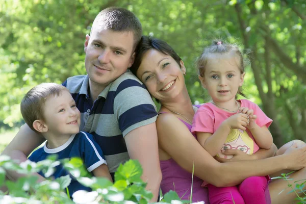 Familj med två barn sitter i gräset — Stockfoto