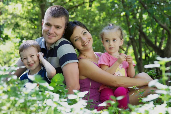 Šťastná rodina se dvěma dětmi sedí — Stock fotografie