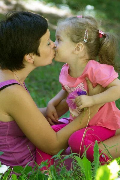 Mutlu anne ve küçük kızı çayırda öpüşme — Stok fotoğraf