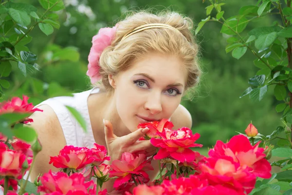 Femme dans la roseraie rose sentant — Photo