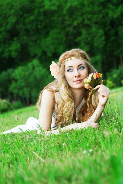 Frau mit Rosen liegt im grünen Gras lizenzfreie Stockfotos