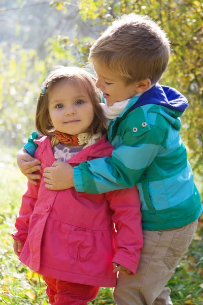 Brother hugging sister in autumn park — Stock Photo, Image