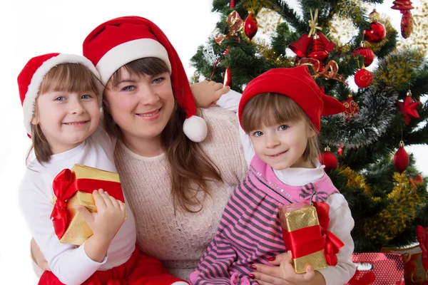 Lächelnde Mutter und zwei Töchter unterm Weihnachtsbaum — Stockfoto