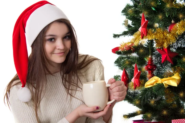 Tienermeisje met koffiemok onder kerstboom — Stockfoto