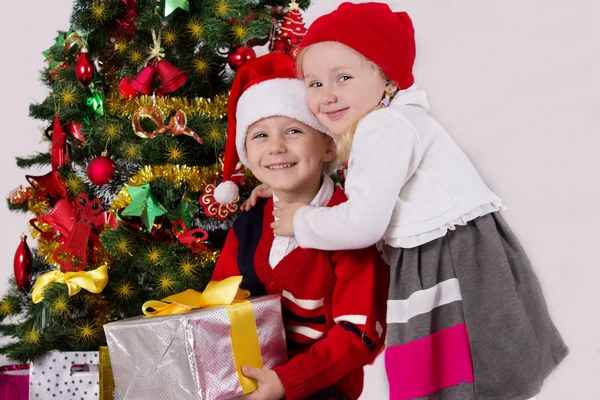 Zus en broer knuffelen onder kerstboom — Stockfoto