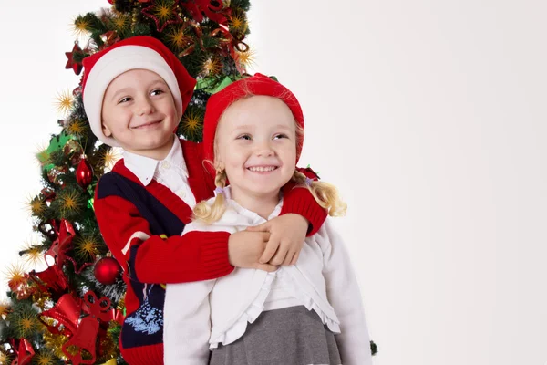 Hermana y hermano abrazándose bajo el árbol de Navidad — Foto de Stock