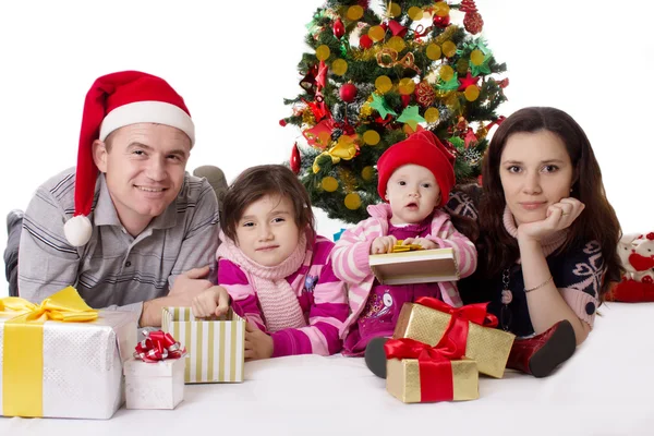 クリスマス ツリーの下で横になっている 2 つの小さな娘と家族 — ストック写真