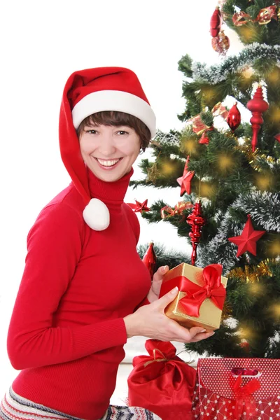 Lachende vrouw in rode santa hatunder kerstboom — Stockfoto