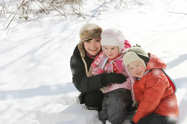 Mère heureuse avec deux enfants couchés dans la neige — Photo