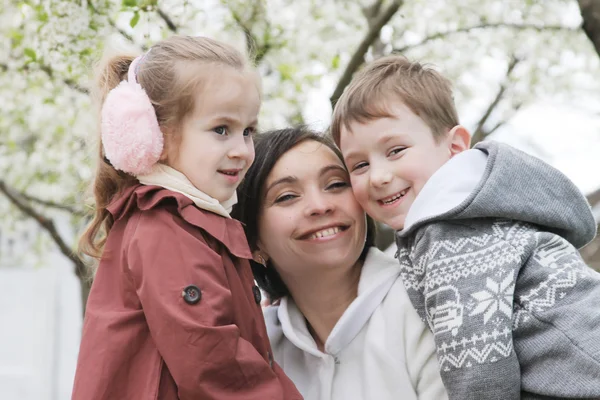Счастливая мать и двое детей обнимаются — стоковое фото