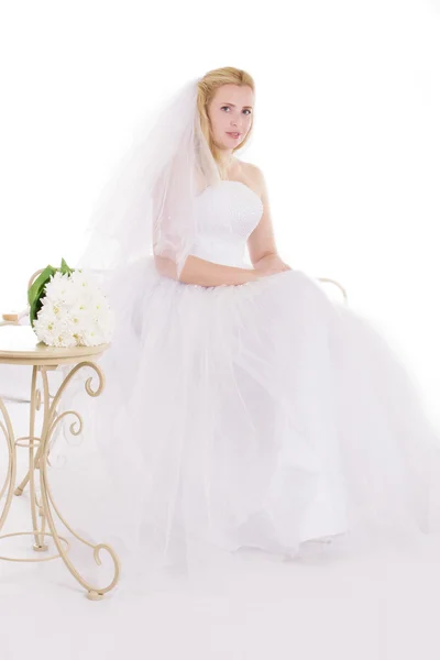 Blonde bride sitting with bouquet — Stock Photo, Image